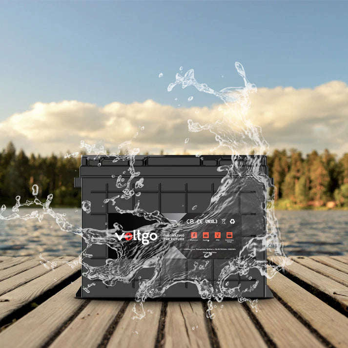 Black Voltgo lithium battery on a wooden dock beside a lake with a water splash effect surrounding the battery.