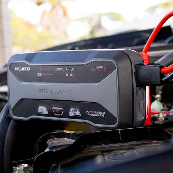 Projecta emergency jump starter attached to a car, with visible branding and features.